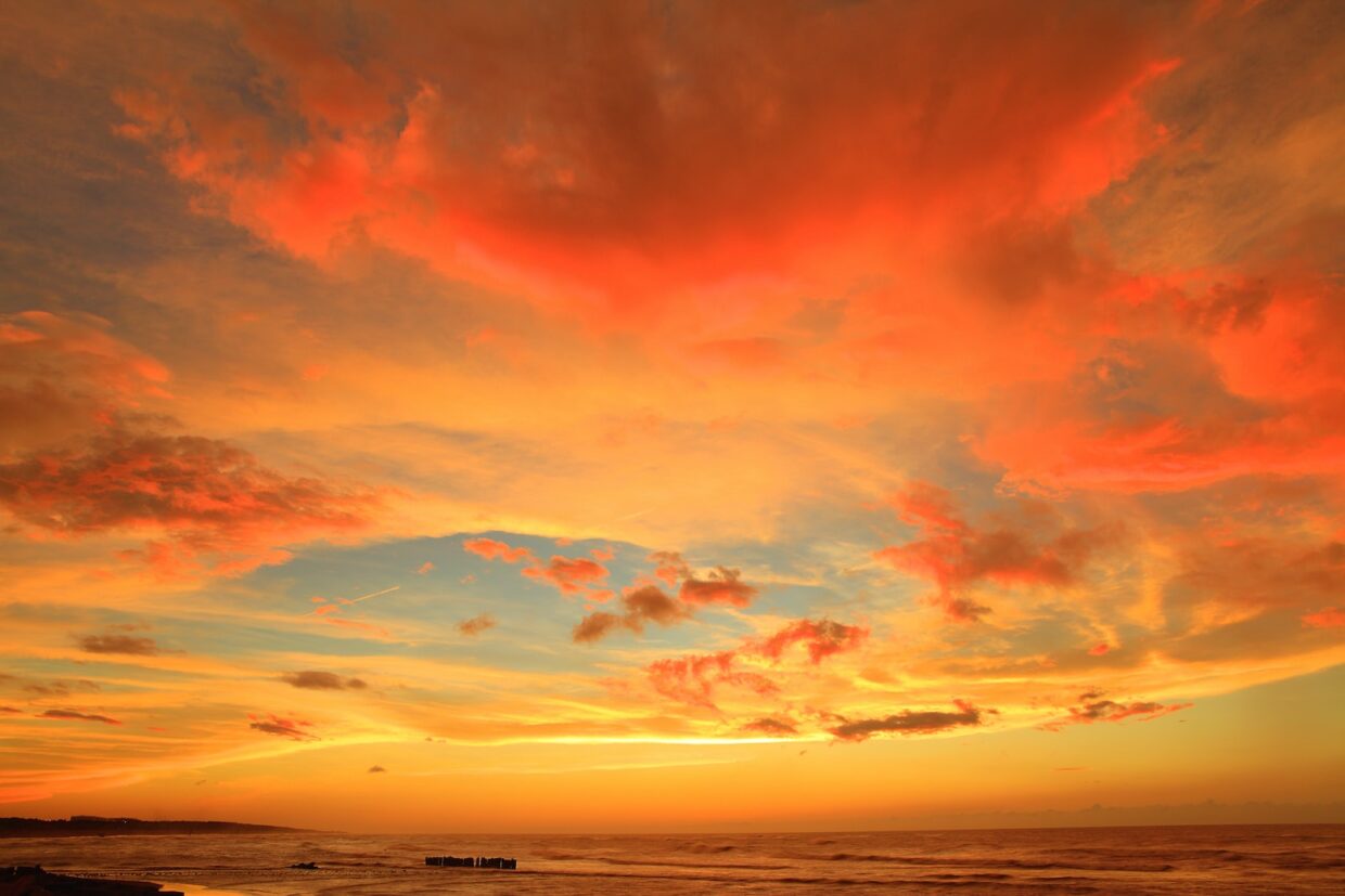 silhouette photo of body of water under orange clouds